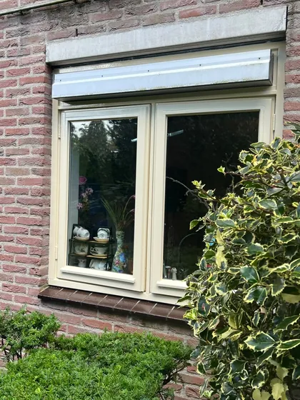 Detail van een bakstenen gevel met opnieuw gelakte witte raamkozijnen