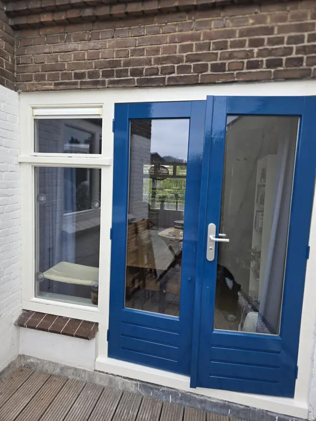Blauw gelakte openslaande achterdeuren met glas, gezien vanuit de woonkamer