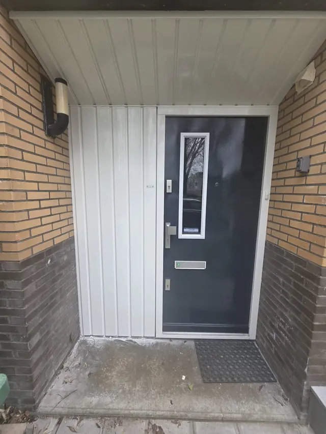 Wit gelakte gevelbekleding naast een donkere voordeur