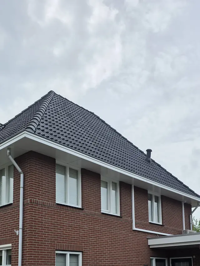 Bakstenen woning met wit gelakte kozijnen en boeiboord